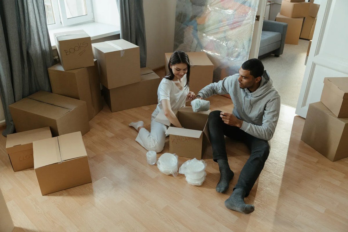 A couple packing cardboard moving boxes in a new home, the moment to update the address on a Portuguese NIF record with Finanças