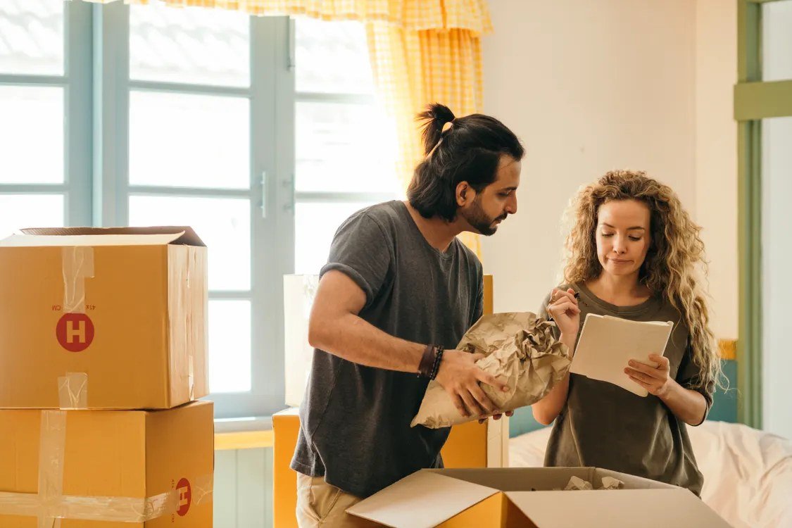 A couple unpacking moving boxes in their new home, the stage most UK citizens reach after arranging their Portuguese NIF from the UK