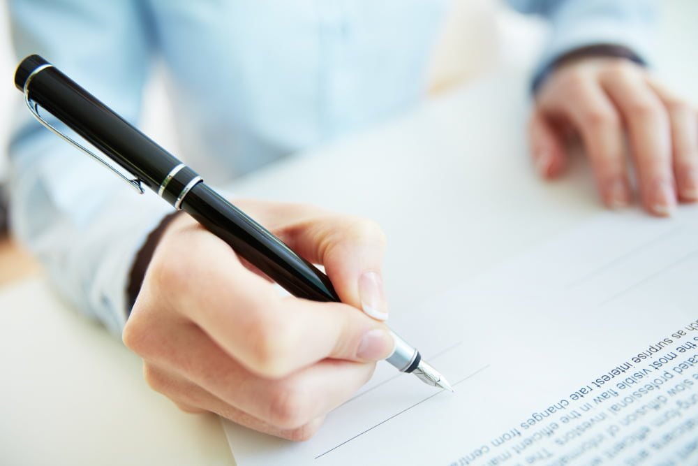A hand signing a document with a fountain pen, the power of attorney signed for a remote Portuguese NIF application