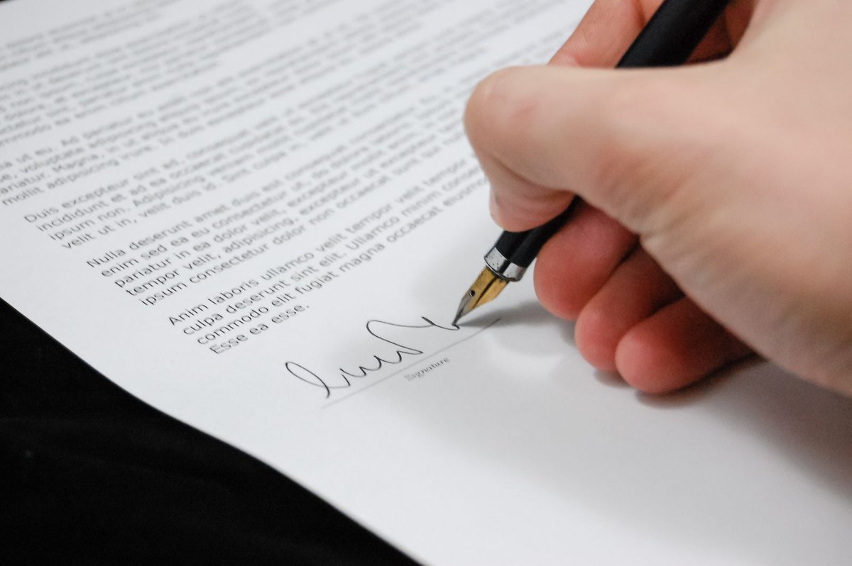 A hand signing a formal document with a fountain pen, the signing moment in the habilitação de herdeiros heirship process in Portugal
