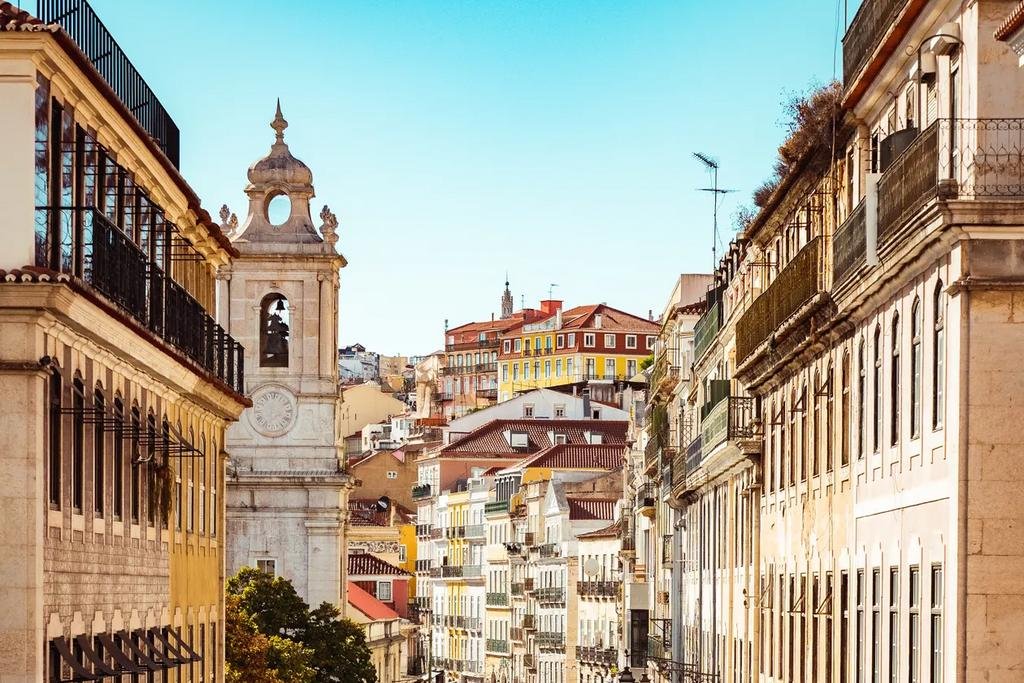 A sunlit street in the Baixa district of Lisbon, Portugal, with a church bell tower and traditional apartment buildings, near the tax offices where a NIF is issued in person