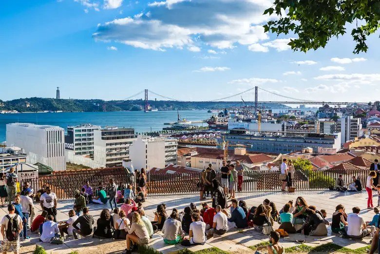 People relaxing at the Miradouro de Santa Catarina viewpoint in Lisbon above the River Tagus, the everyday life British movers settle into after getting a NIF