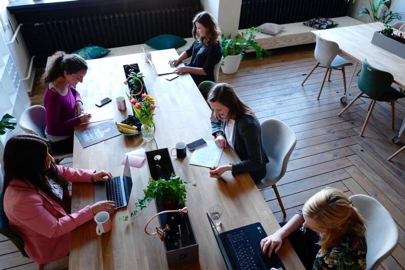 Remote workers with laptops around a long shared table in a coworking space, the working routine many digital nomad visa residents settle into in Portugal