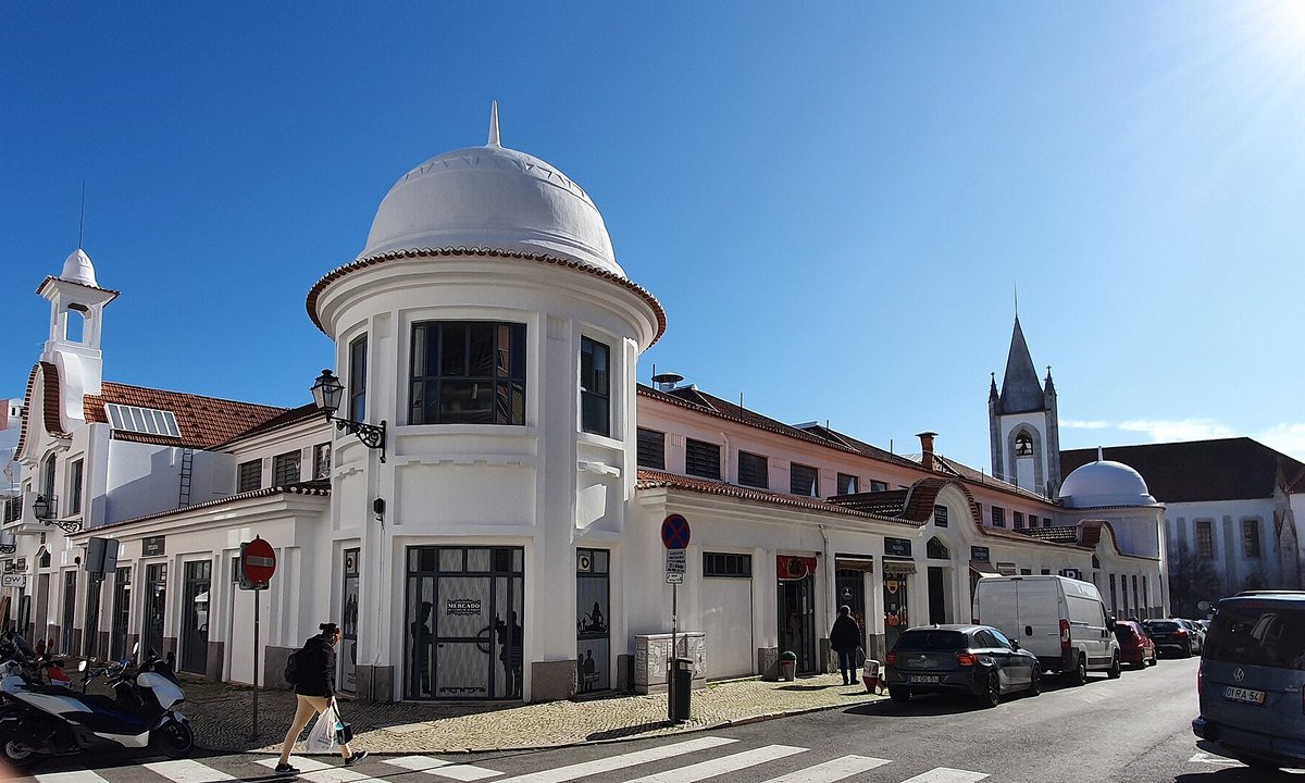 The white domed Mercado de Campo de Ourique market hall on a sunny street in Lisbon, Portugal, an everyday neighbourhood landmark for new residents