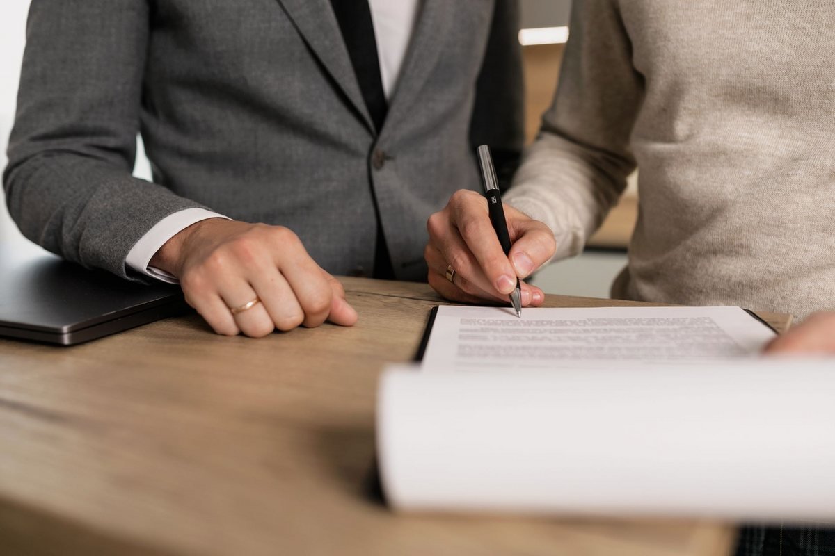 Two people signing bank account paperwork at a desk, the short signing session that follows once a Portuguese NIF is ready